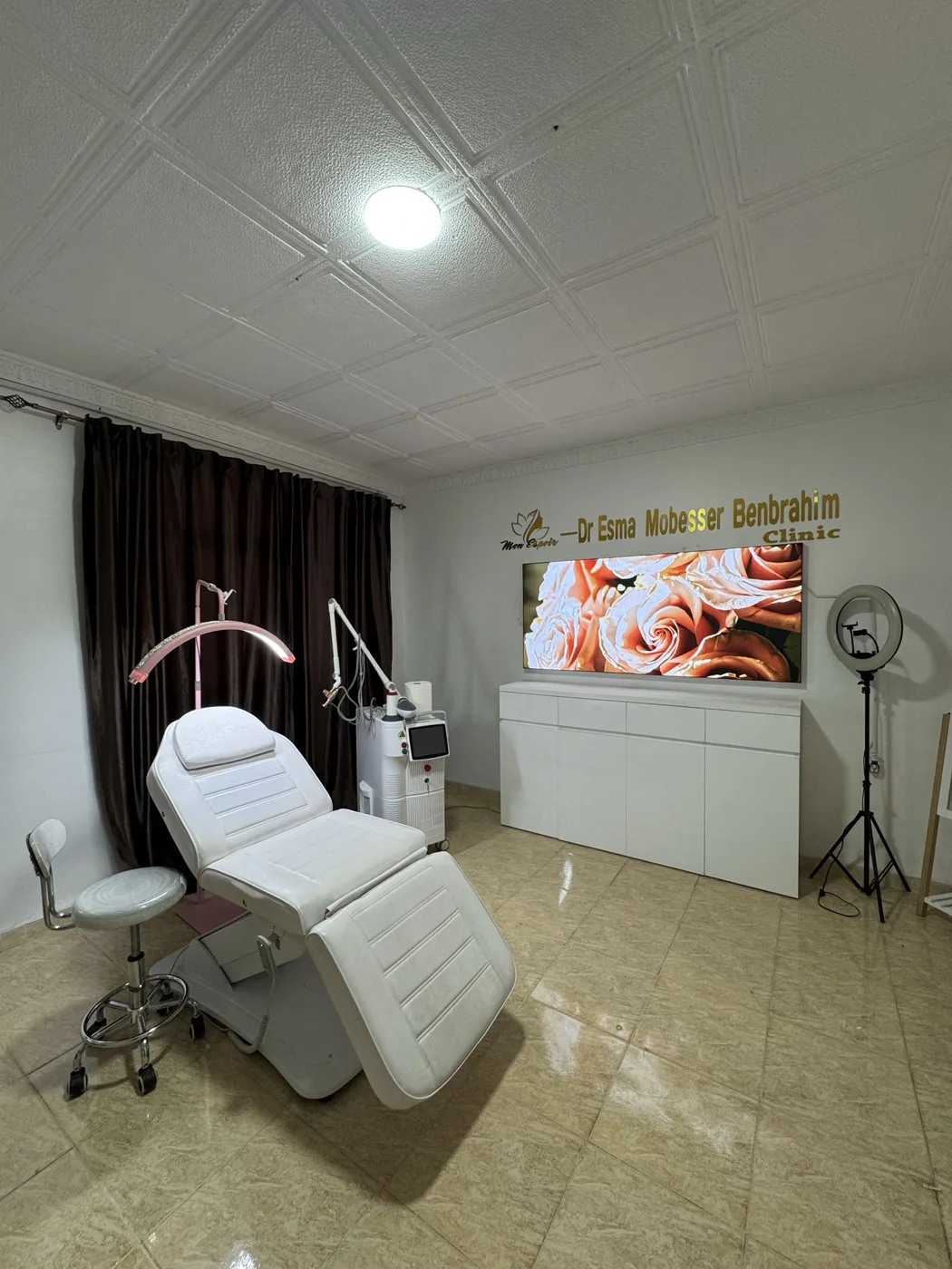 Cabine de médecine esthétique avec un grand caisson lumineux de roses au-dessus du meuble