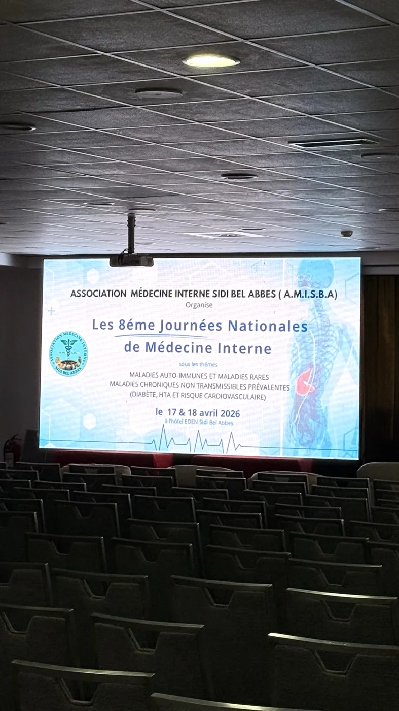 Salle de conférence avec le visuel des 8es Journées Nationales de Médecine Interne projeté sur grand écran
